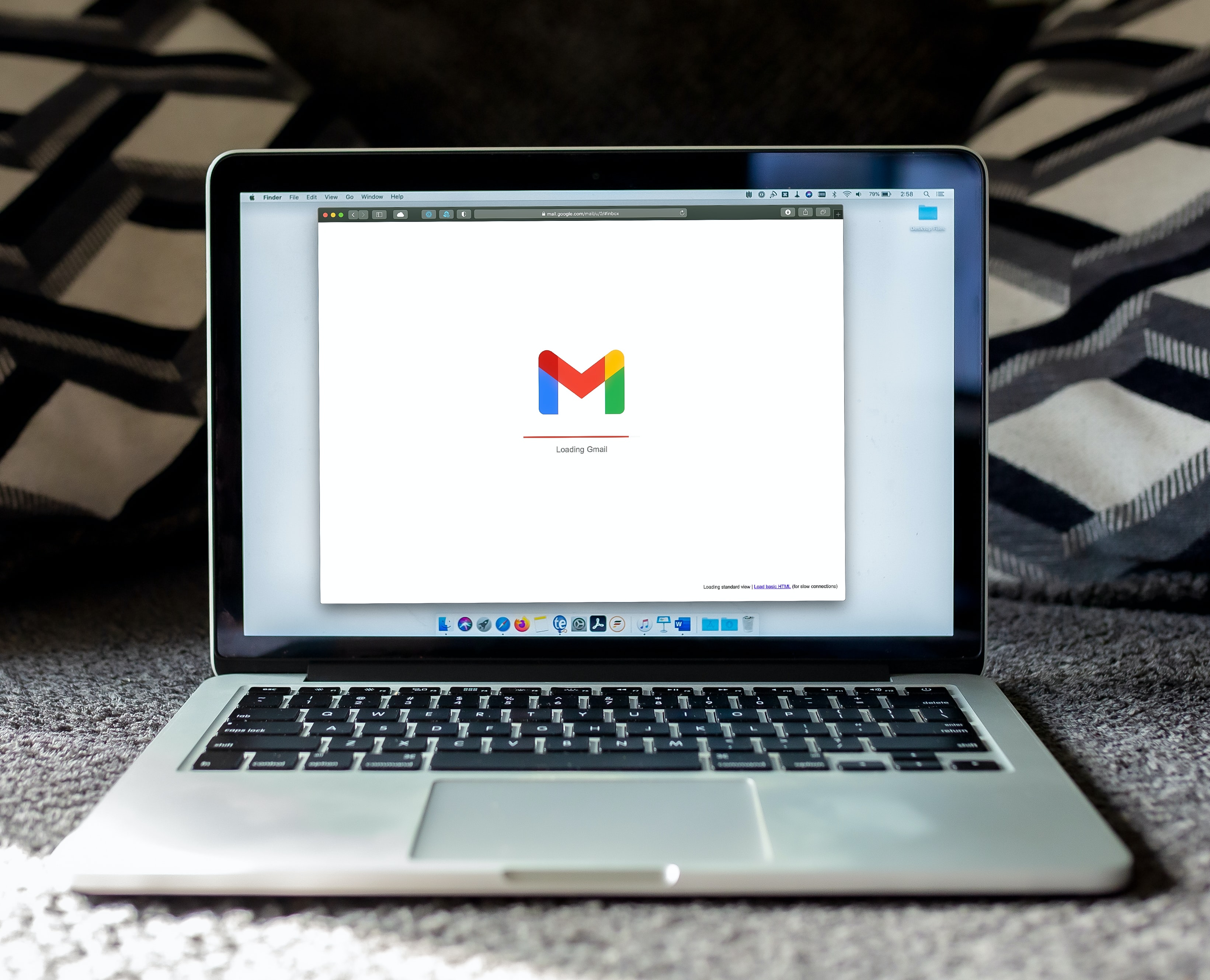 Photo by Solen Feyissa on Unsplash. It's an image of a Macbook with Gmail open. The computer is placed on a cute carpet, giving a cozy feeling. Because carpets are cozy? Also, there's blankets in the background